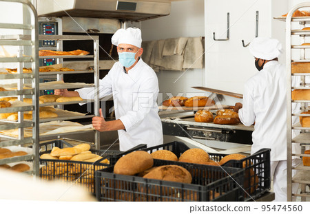 men in chefs uniform with bread in shovel and trolley in bakehouse during epidemic men in chefs uniform with bread in shovel and trolley in bakehouse during epidemic 95474560