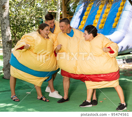 Men and women in sumo suits fighting in outdoor amusement park 95474561