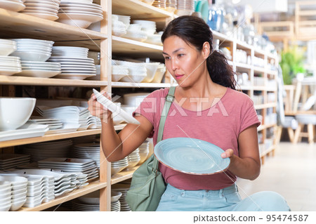 Woman choosing plates in store Woman choosing plates in store 95474587