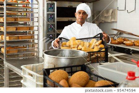 Male baker holding crate with baked bread 95474594