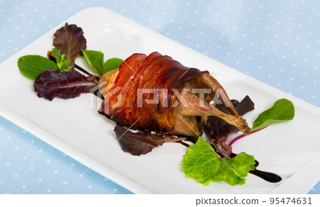Image of baked in bacon quail with balsamic sauce on the plate 95474631