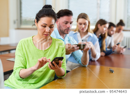 Fellow students play with their smartphones 95474643