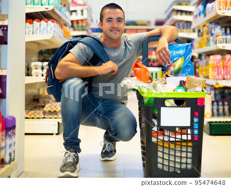 Portrait of man with full grocery cart who came to the supermarket to make purchases 95474648
