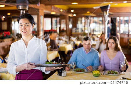 Polite smiling asian waitress inviting to cozy restaurant Polite smiling asian waitress inviting to cozy restaurant 95474746