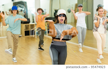 Emotional brunette teen girl dancing hip-hop with group 95474923