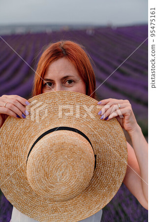 Close up portrait of a happy young woman in a dress on blooming fragrant lavender fields with endless rows. . Bushes of lavender purple fragrant flowers on lavender fields. 95475161