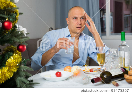 Lonely man drinking alcohol at the christmas table Lonely man drinking alcohol at the christmas table 95475207