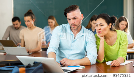 Group of adult students sitting at tables in classroom Group of adult students sitting at tables in classroom 95475521