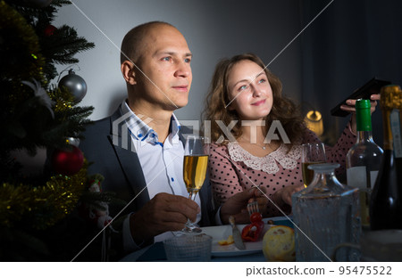 Happy couple drink champagne and watch TV on Christmas night Happy couple drink champagne and watch TV on Christmas night 95475522