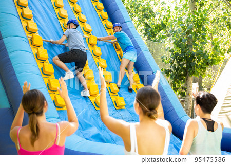 Men climbing up on slide in adventure park 95475586