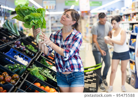 Woman choosing lettuce in supermarket Woman choosing lettuce in supermarket 95475588