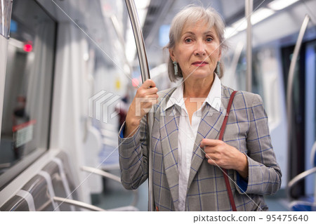 Senior lady standing in metro train 95475640