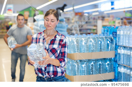 Portrait of attractive woman choosing water in bottle at supermarket Portrait of attractive woman choosing water in bottle at supermarket 95475698