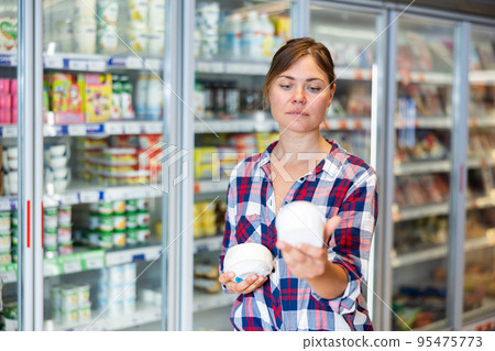 Woman shopping in supermarket, choosing dairy products 95475773
