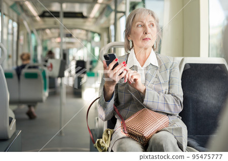 Woman with smartphone sitting in tram 95475777