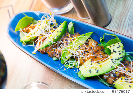 Delicious salmon tartare garnish with avocado on blue plate Delicious salmon tartare garnish with avocado on blue plate 95476017