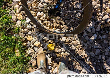 Mud on boots and on bicycle wheels after a muddy stretch of road Mud on boots and on bicycle wheels after a muddy stretch of road 95476116