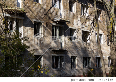 Abandoned three-story brick house with broken windows after resettlement 95476136