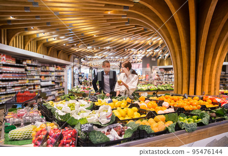 Positive young couple in the supermarket, took fresh apples on the counter Positive young couple in the supermarket, took fresh apples on the counter 95476144