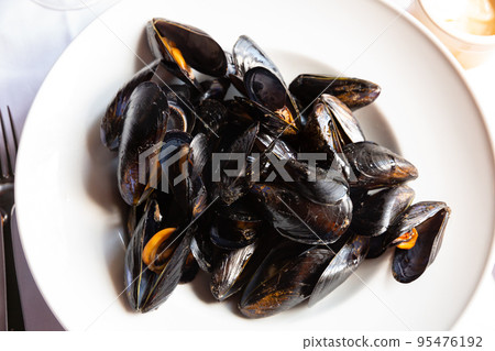 Delicious grilled mussels on plate, served with ali-oli sauce Delicious grilled mussels on plate, served with ali-oli sauce 95476192