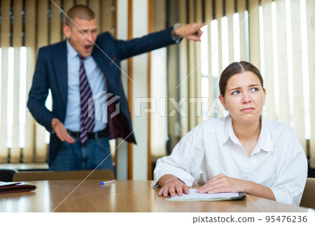 Emotional young boss berates his secretary girl in the conference room 95476236