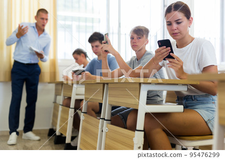 Teenager students sitting in class room with smartphones 95476299