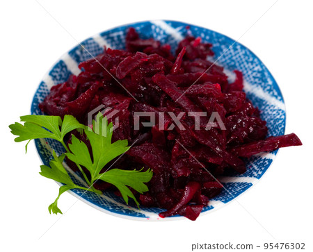Salad of grated baked beetroot on plate with fresh parsley 95476302
