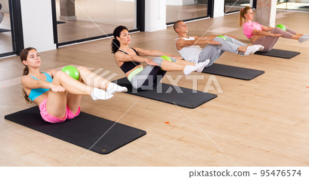 Four people doing raise crunch exercise with pilates balls Four people doing raise crunch exercise with pilates balls 95476574