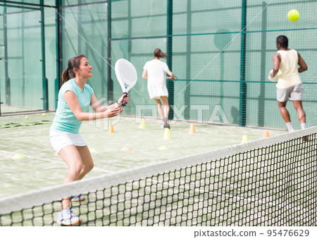 Training while playing on tennis court. Woman learning to play paddle 95476629