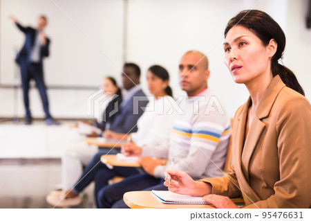 Asian businesswoman sitting at corporate seminar in conference room Asian businesswoman sitting at corporate seminar in conference room 95476631