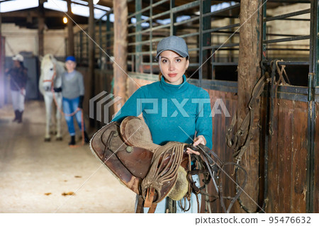 Woman horse breeder with leather saddle Woman horse breeder with leather saddle 95476632