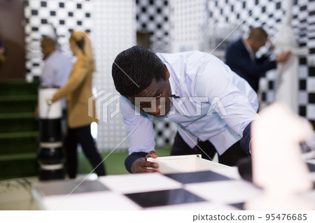 Man looking for a key to solve a puzzle in quest room Man looking for a key to solve a puzzle in quest room 95476685