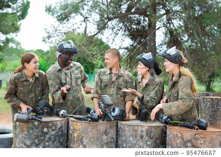 Smiling friends chatting after successful paintball match Smiling friends chatting after successful paintball match 95476687