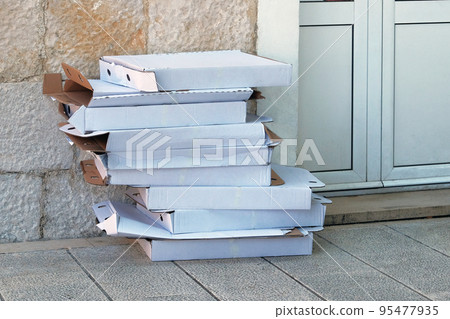 Empty pizza boxes are folded for further sorting and processing. Cardboard and waste paper is collected and packaged for recycling. Urban Recycle. 95477935