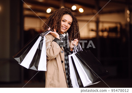 Stylish woman with shopping bags 'near mall. Young woman after shopping. Winter holidays. 95478012
