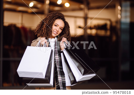 Stylish woman with shopping bags 'near mall. Young woman after shopping. Winter holidays. Stylish woman with shopping bags 'near mall. Young woman after shopping. Winter holidays. 95478018