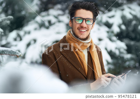 Outdoor close up portrait of young beautiful men. Smiling young man having fun outdoors. Snowfall. 95478121