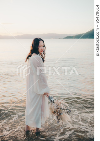 Photo of a woman standing by the beach Photo of a woman standing by the beach 95479014
