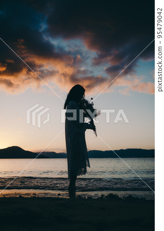 Silhouette photo of a woman standing on the beach 95479042