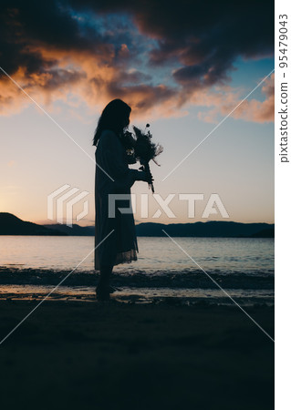 Silhouette photo of a woman standing on the beach Silhouette photo of a woman standing on the beach 95479043