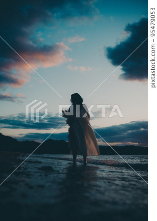 Silhouette photo of a woman standing on the beach 95479053