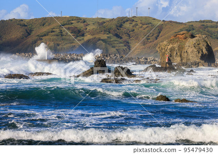 Waves crashing into a small fishing port 95479430