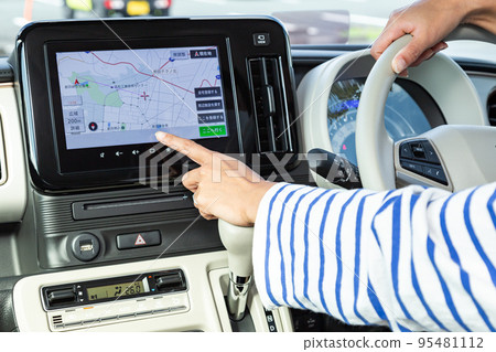 The hand of a woman operating a car navigation system 95481112