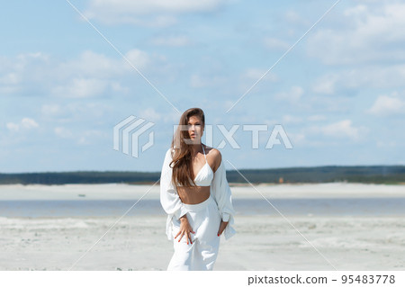 Beautiful woman standing on seashore Beautiful woman standing on seashore 95483778