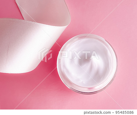 Skincare cosmetics, face cream moisturiser jar and white silk ribbon on pink background, beauty product flatlay close-up Skincare cosmetics, face cream moisturiser jar and white silk ribbon on pink background, beauty product flatlay close-up 95485086