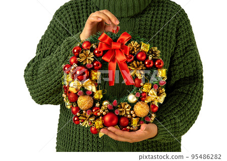 Woman in a green knitted sweater with a Christmas wreath in her hands, isolated Woman in a green knitted sweater with a Christmas wreath in her hands, isolated 95486282