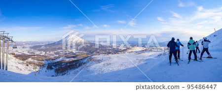 [Panorama photo] Mt. Yotei and skiers in the early afternoon (Hokkaido, Niseko) 95486447