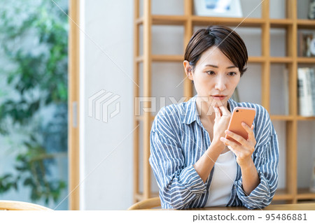中間女人在客廳裡操作智能手機 95486881