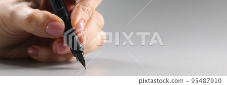 Person holding black feather pen, sharp tip, tool for writing 95487910
