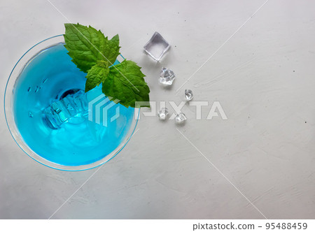 Top view of blue cocktail in martini glass with ice cubes and mint 95488459